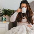 A woman drinking a Hot Soothing Drink made with Herbion Respiratory Care Herbal Granules 