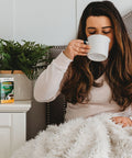 A woman drinking a Hot Soothing Drink made with Herbion Respiratory Care Herbal Granules 